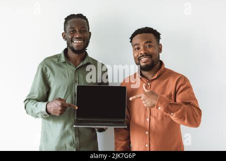 Two Happy Black Guys Showing Laptop Screen Over White Background Stock Photo