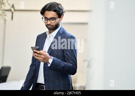 Busy indian business man using smartphone working standing in office. Stock Photo