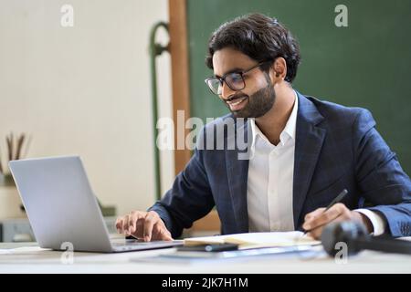 Happy arabic indian young business man working watching webinar on laptop. Stock Photo