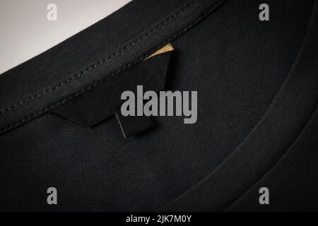 Black blank clothes label on black fabric texture background. Top view Stock Photo