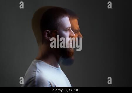 Side view portrait of two-faced man in calm serious and angry screaming expression. Different emotion inside and outside mood. Internally suffering, dissociative identity disorder. Double exposure. Stock Photo