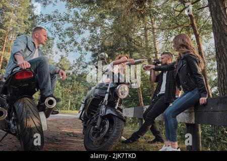 A company of friends travel together on motorcycles, stopped at the roadside, have fun and drink tea Stock Photo