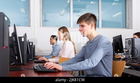 Side view of focused female and male students working on computers in classroom Stock Photo