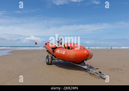 Rib boat on the beach. A Royal National Lifeboat Institute (RNLI) Rib sits on a Cornish beach ready to rescue any swimmers in trouble in the sea. Stock Photo