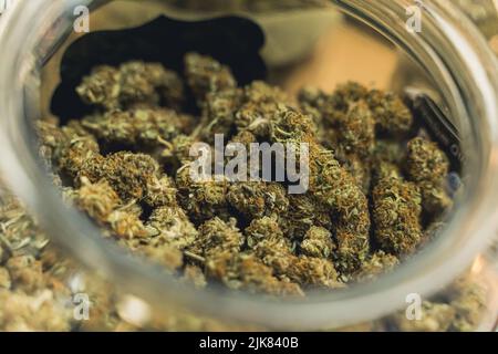Closeup shot of dry and trimmed cannabis buds stored in a transparent glass jar. Alternative medicine concept. Anxiety relief. High quality photo Stock Photo