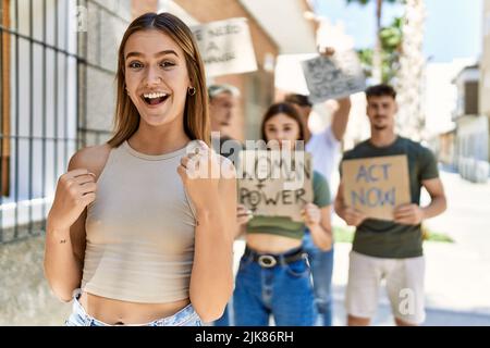 Group of people protesting and giving slogans at the street screaming proud, celebrating victory and success very excited with raised arms Stock Photo