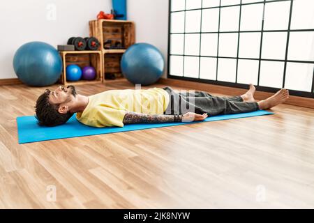 Young hispanic man lying on the floor relaxing at sport center. Stock Photo