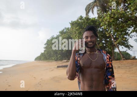 A vacationer makes a phone call while walking on the sand of the beach. Stock Photo
