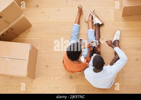 Focusing on our future. a young couple sitting on the floor while looking at an ultrasound picture at home. Stock Photo