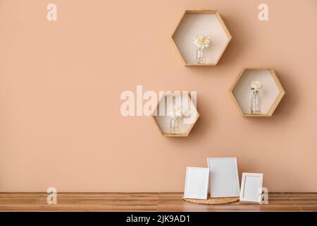 Blank photo frames on kitchen counter and shelves with beautiful peony flowers on beige wall Stock Photo