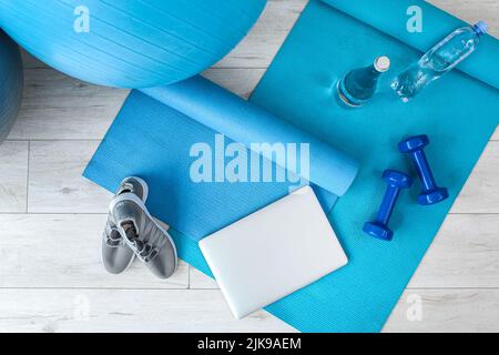 Laptop and sports equipment on yoga mat Stock Photo