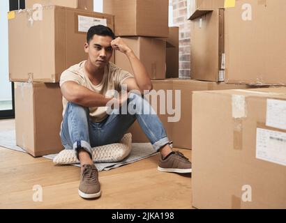 The simple lack of her is more to me. a young man being upset while sitting on the floor at home. Stock Photo