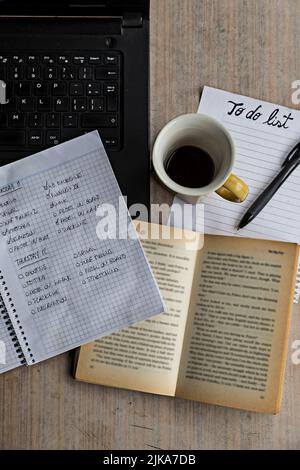 Laptop, notebook, pen, book, coffee cup and to-do list on a wooden table. Stock Photo