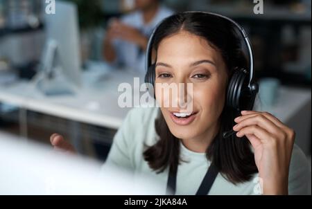 Theres no waiting around when shes on the line. a young woman using a headset and computer in a modern office. Stock Photo