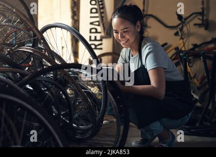 Makeup has never thrilled me. a young happy young woman fixing a bike at a bicycle repair shop. Stock Photo