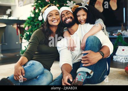 The spirit of Christmas summed up in one moment. Portrait of a happy young family celebrating Christmas at home. Stock Photo