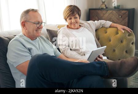 Taking a trip down digital memory lane. a mature relaxing while using a digital tablet. Stock Photo