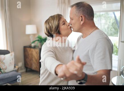 Your kisses let me know that I am home. a mature couple slow dancing in their lounge. Stock Photo