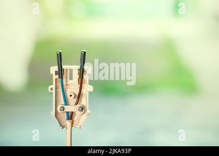 Connecting the wires of an electrical appliance into an electrical plug. Disassembled white plastic electrical plug close-up on a colored blurred back Stock Photo