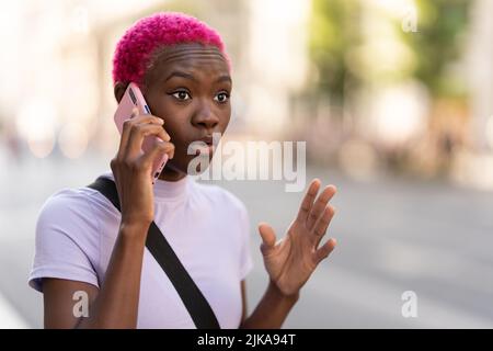 Young african woman talking energetically on her mobile outdoors Stock Photo
