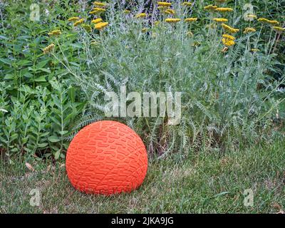 grooved and textured, heavy rubber slam ball filled with sand in a backyard, exercise and functional fitness concept Stock Photo