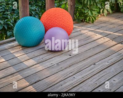 three heavy slam balls filled with sand on a backyard deck with morning light, exercise and functional fitness concept Stock Photo