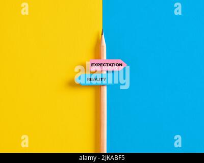 Reality vs expectation contrast or choice. Pencil with direction indicator stickers showing the distinction between expectations and reality. Stock Photo