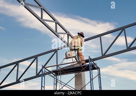 A workers are using Inverter welding machine. Equipment for welding both ferrous and non-ferrous metals. MMA welding on the steel roof structure. Stock Photo