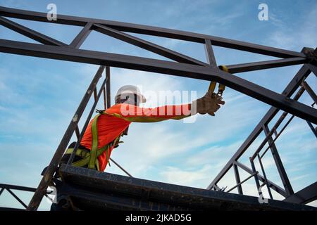 A worker are using Fall arrestor device for worker with hooks for safety body harness on onstruction site. Stock Photo