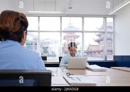 Handsome young Vietnamese businessman working on laptop Stock Photo
