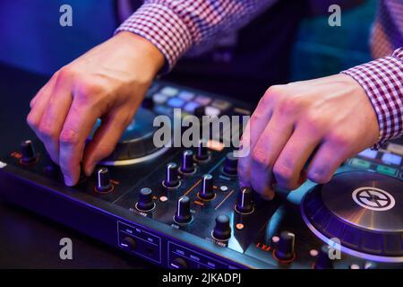 Dj playing music with turntables and sound mixer on stage in night club Stock Photo