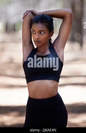 My health comes first. an attractive young woman standing and stretching before her workout outdoors. Stock Photo