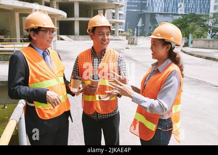 Cheerful female engineer talking to her coworkers Stock Photo