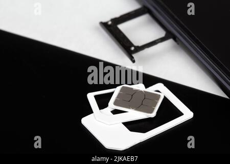 SIM card on the sim card tray of a smartphone and sim card adaptors Stock Photo