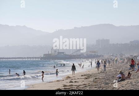 Los Angeles, 12 July 2022: People enjoy the afternoon sun at Venice Beach, Los Angeles, with misty hills in the background Stock Photo