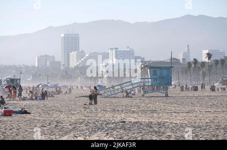 Los Angeles, 12 July 2022: People enjoy the afternoon sun at Venice Beach, Los Angeles, with misty hills in the background Stock Photo