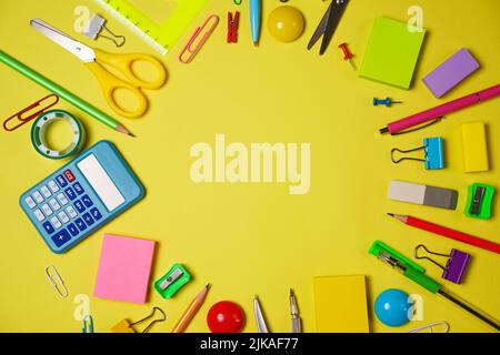 School or office workspace with colored supplies in form circle with space for text on a yellow background. Flat layout. Stock Photo