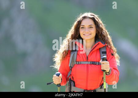 Happy hiker in red walking towards camera in the mountain Stock Photo