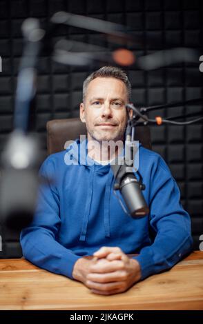 Portrait of mature radio host speaking in microphone while moderating a