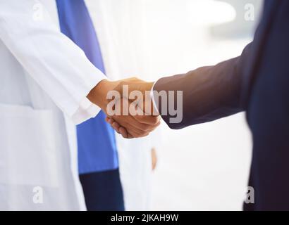 Im your answer, if you move me, Im your dancer. a doctor shaking hands with a businessman in a hospital. Stock Photo