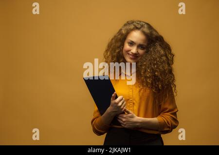 Studio portrait of happy businesswoman holding folder and papers, on yellow background, Business concept. Accountant, copy space. Stock Photo