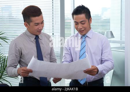 Young engineers discussing blueprint of new building Stock Photo