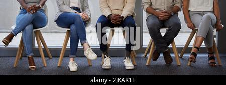 Our stories are different but were chasing the same dream. a diverse group of businesspeople waiting in line for an interview. Stock Photo