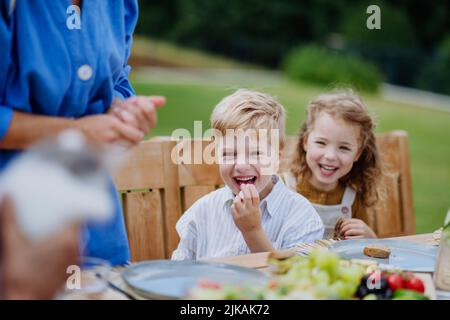 Happy kids enjoying garden party with family, having fun and eating together. Stock Photo