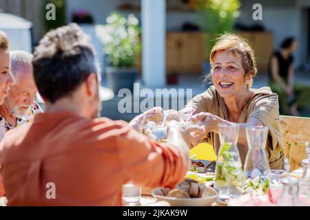 Multi generation family having garden party celebration, grandmother giving salad to her son. Stock Photo