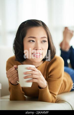 Pensive Vietnamese young woman with a cup of coffee Stock Photo