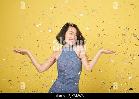 Lovely happy young woman standing in falling confetti Stock Photo