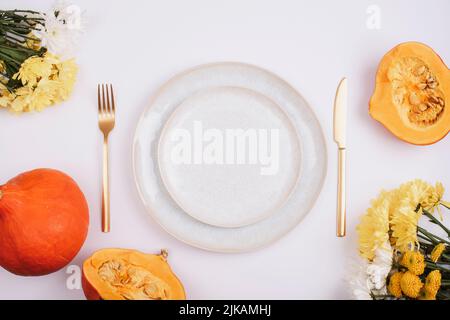 Stylish table setting, yellow dahlia flowers, pumpkins and plate on white table. Top view, flat lay Stock Photo