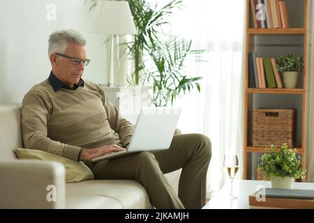 Senior man working on laptop at home Stock Photo