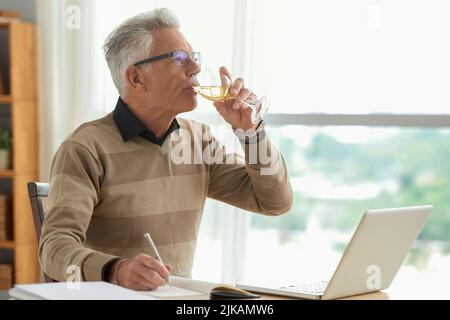 Professional writer drinking wine when working on new novel Stock Photo